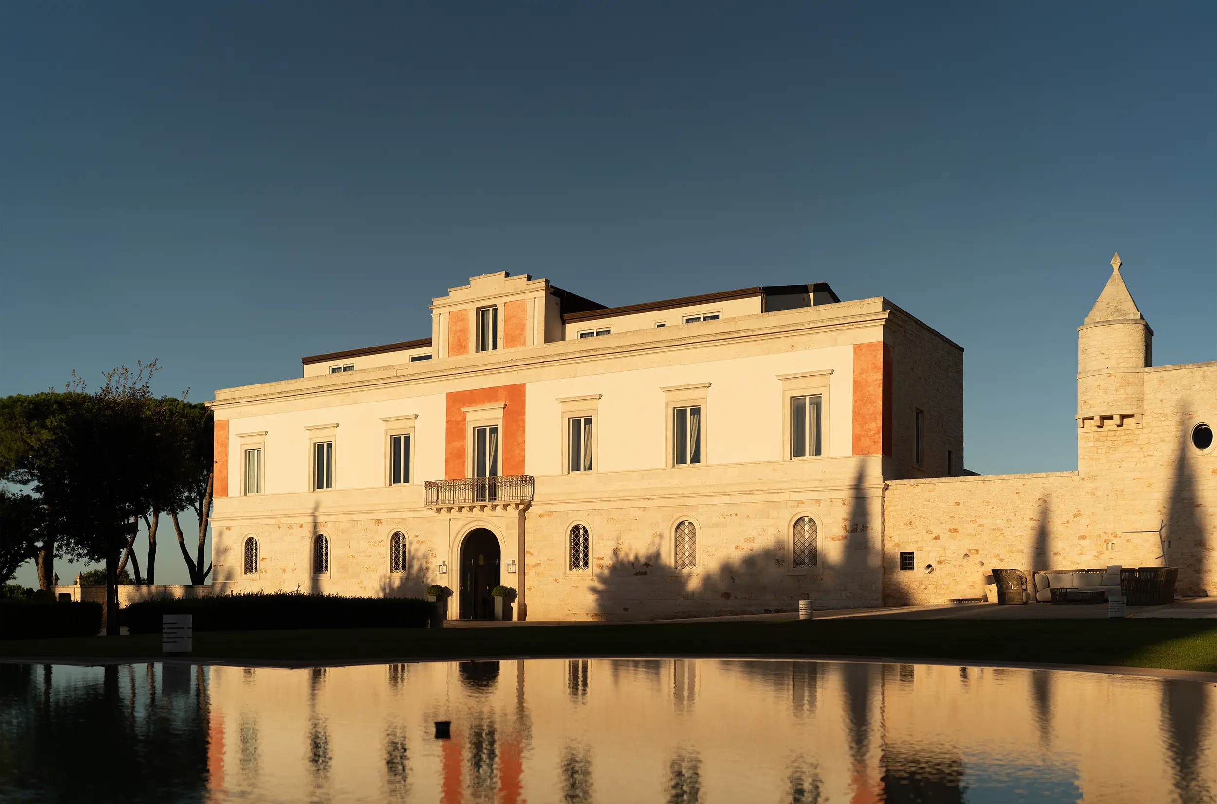 Relais Il Santissimo a Turi con palazzo storico illuminato e riflesso sull’acqua.