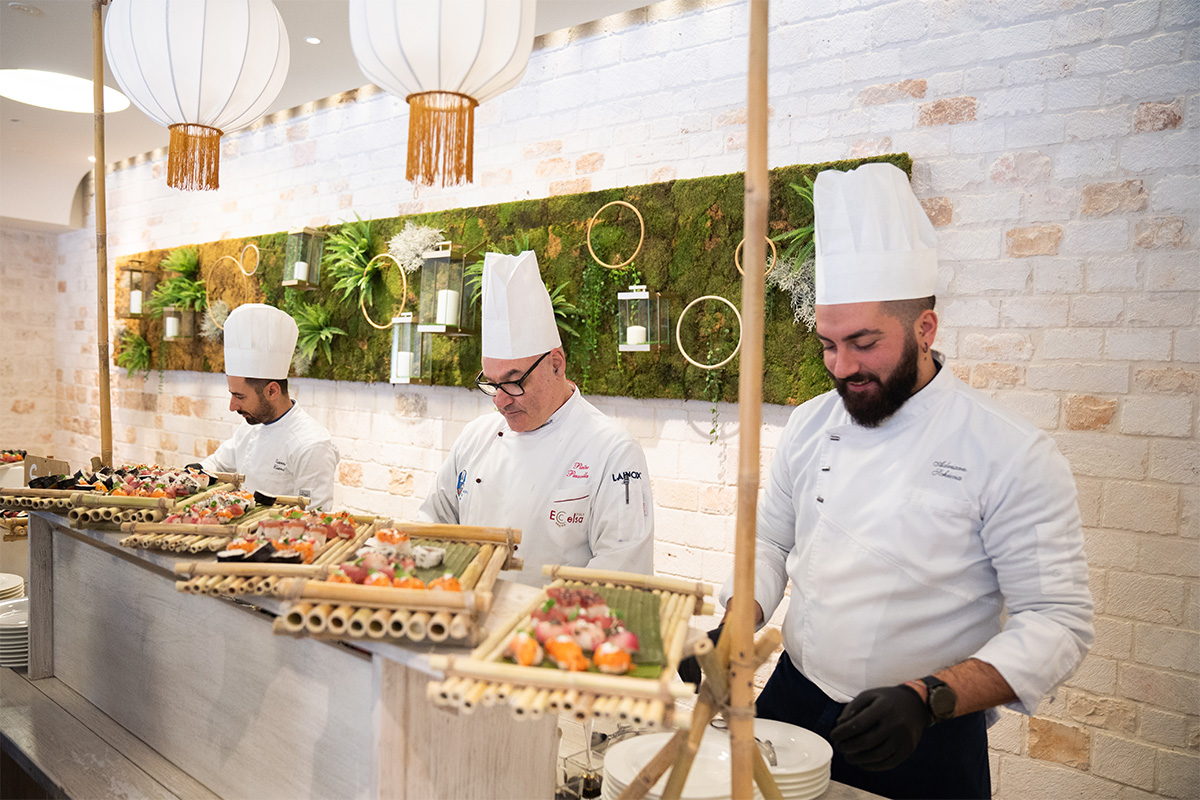 Chef del catering interno de Il Santissimo preparano piatti gourmet per un evento.