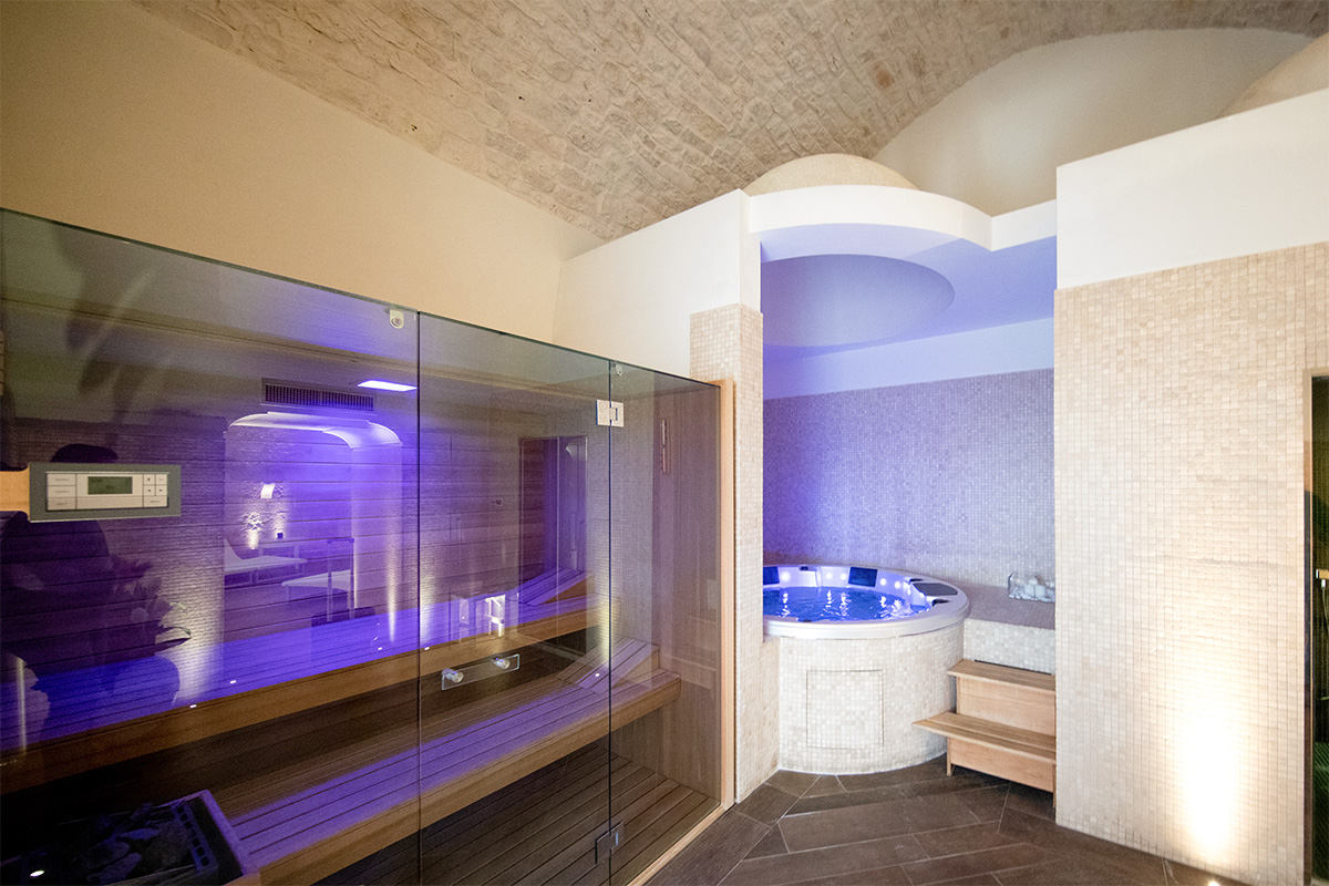 Area spa dell’hotel Relais Il Santissimo con sauna, vasca idromassaggio e pareti in pietra.