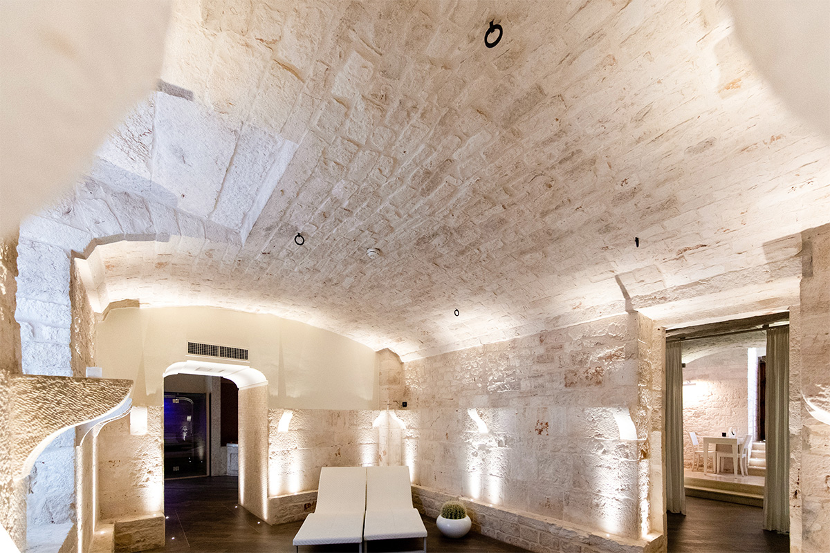 Sala relax in pietra nella spa, con lettini e volte storiche.