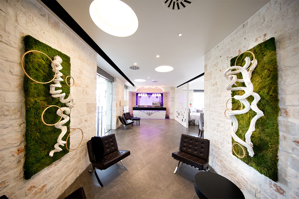 Reception at the Alcova dei Sensi spa at Relais Il Santissimo, with stone walls and natural panels.