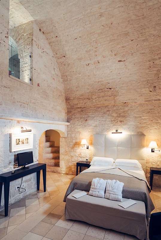 Zona letto della suite con volte in pietra e arredi d’epoca.