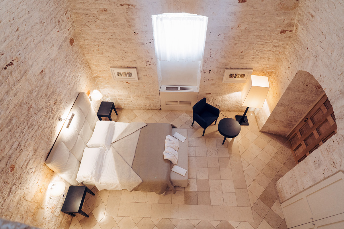 View from above of the Suite del Massaro with bed, stone walls, and period furnishings.