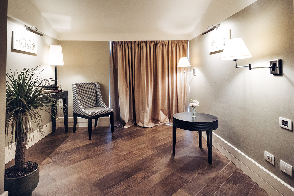 Zona lounge con poltrona, tavolino e tende eleganti.