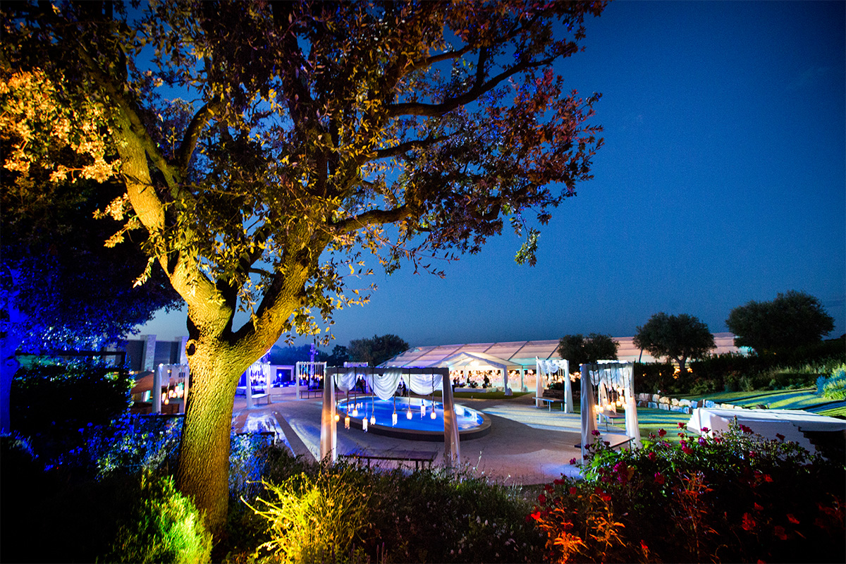 Evening event at Il Santissimo Arena della Gioia with scenic pool and illuminated garden.