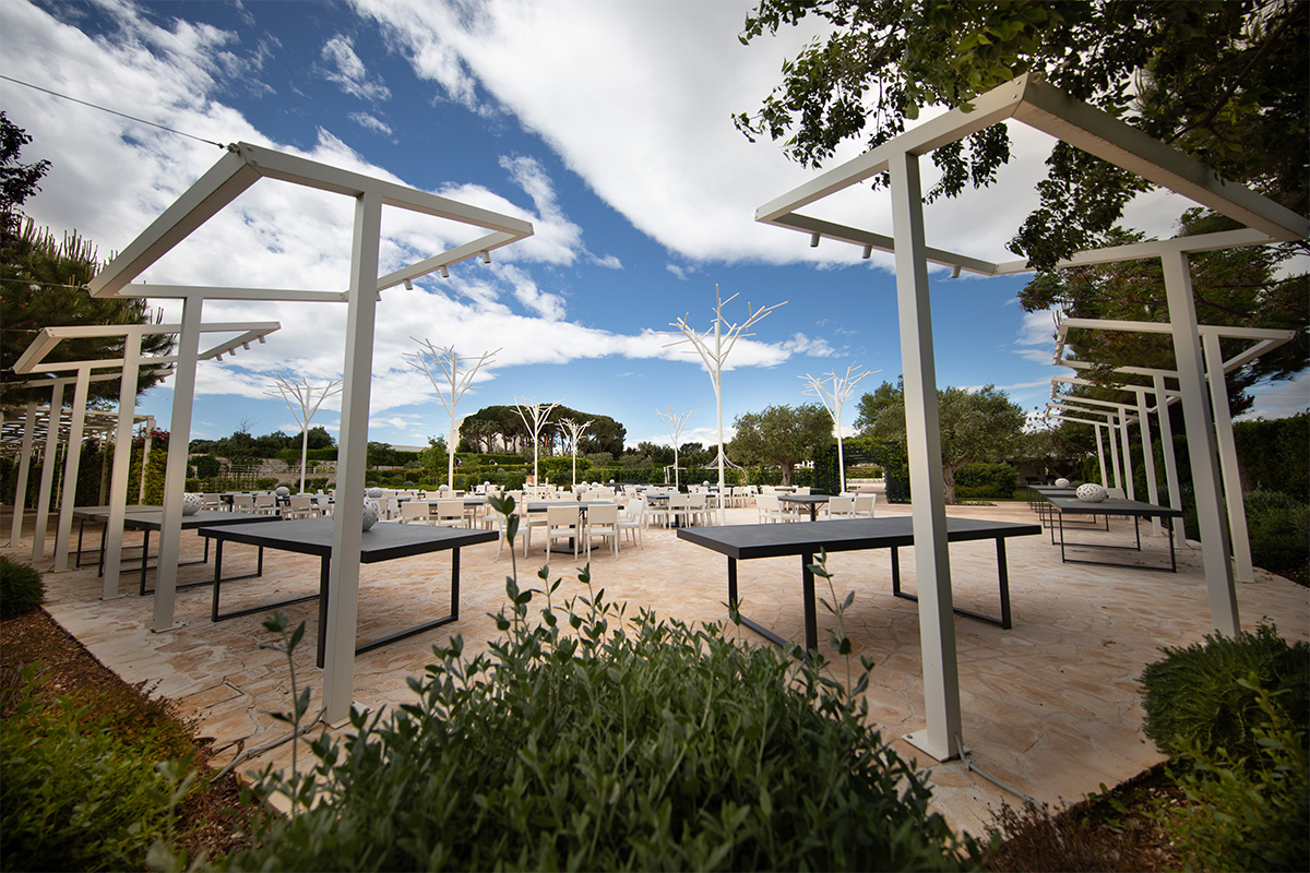Outdoor event space with white pergolas and garden.