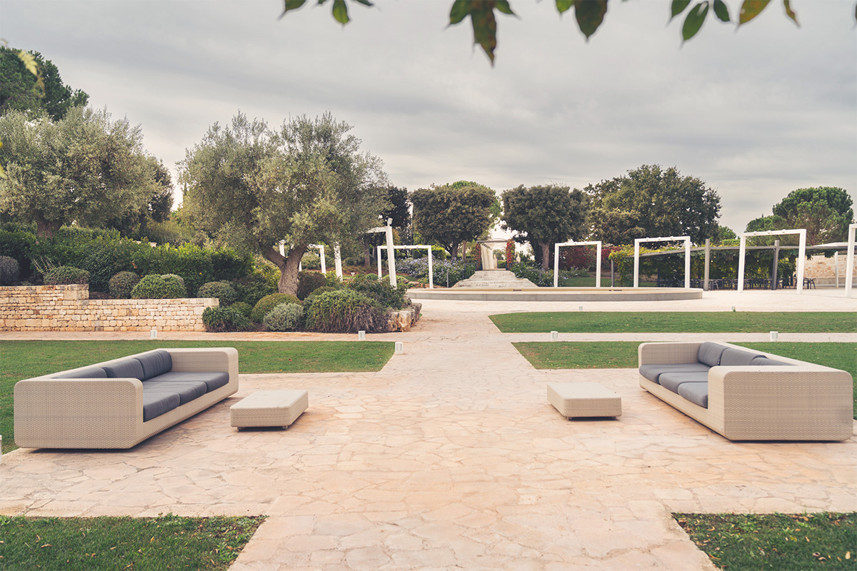 Outdoor lounge of Arena della Gioia with sofas and garden pathways.