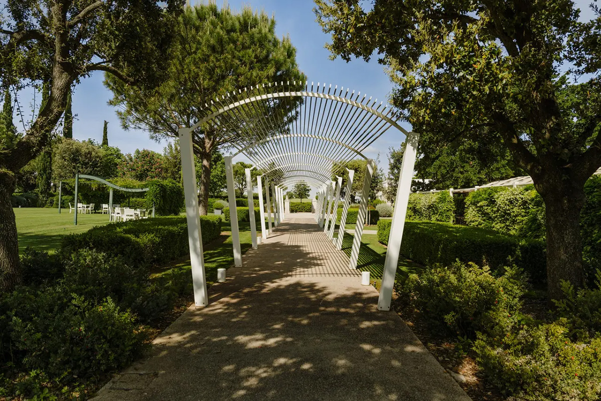 Pergola walkway in the garden with hedges and trees for open-air celebrations.