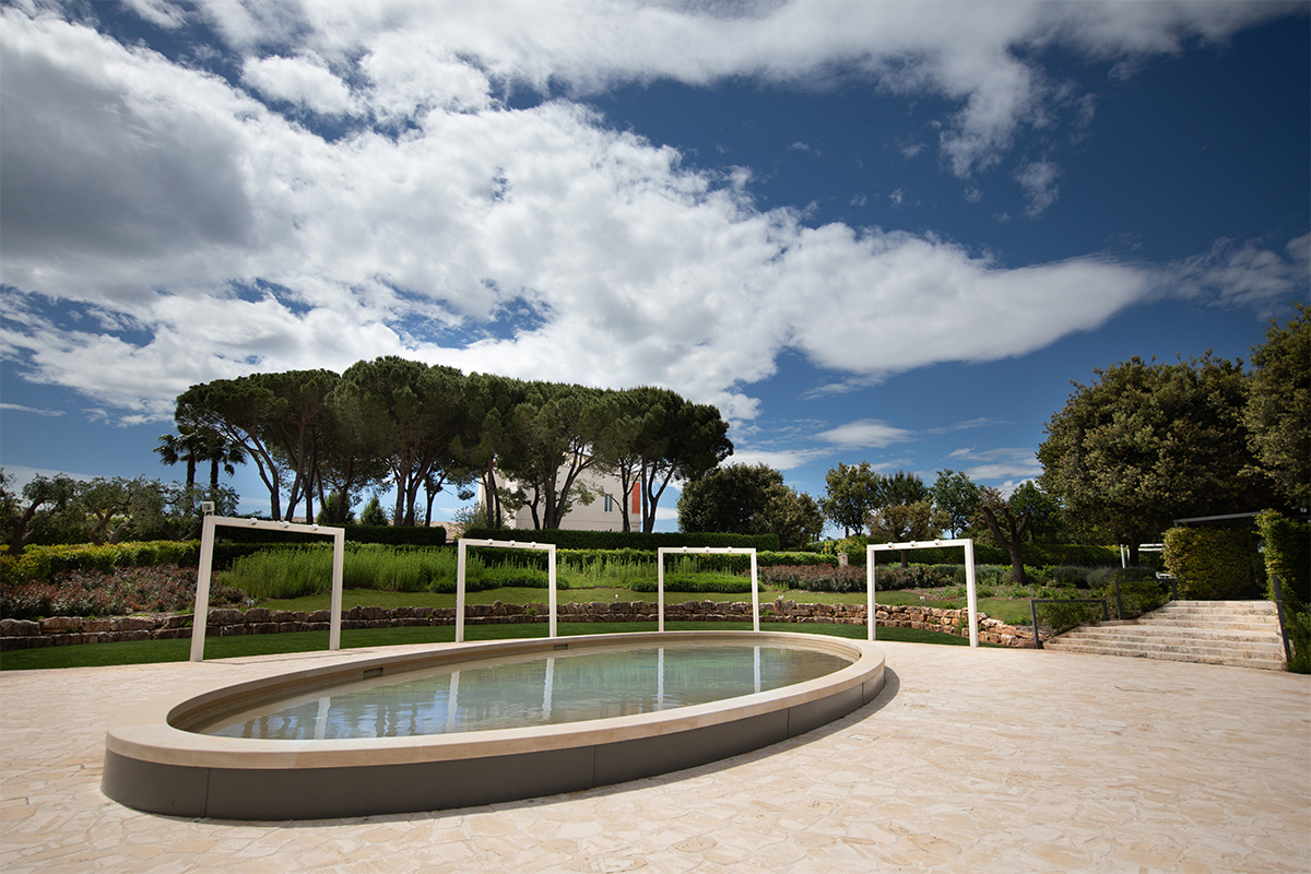 Scenic pool in the Arena della Gioia garden, with stone floor and white pergolas.