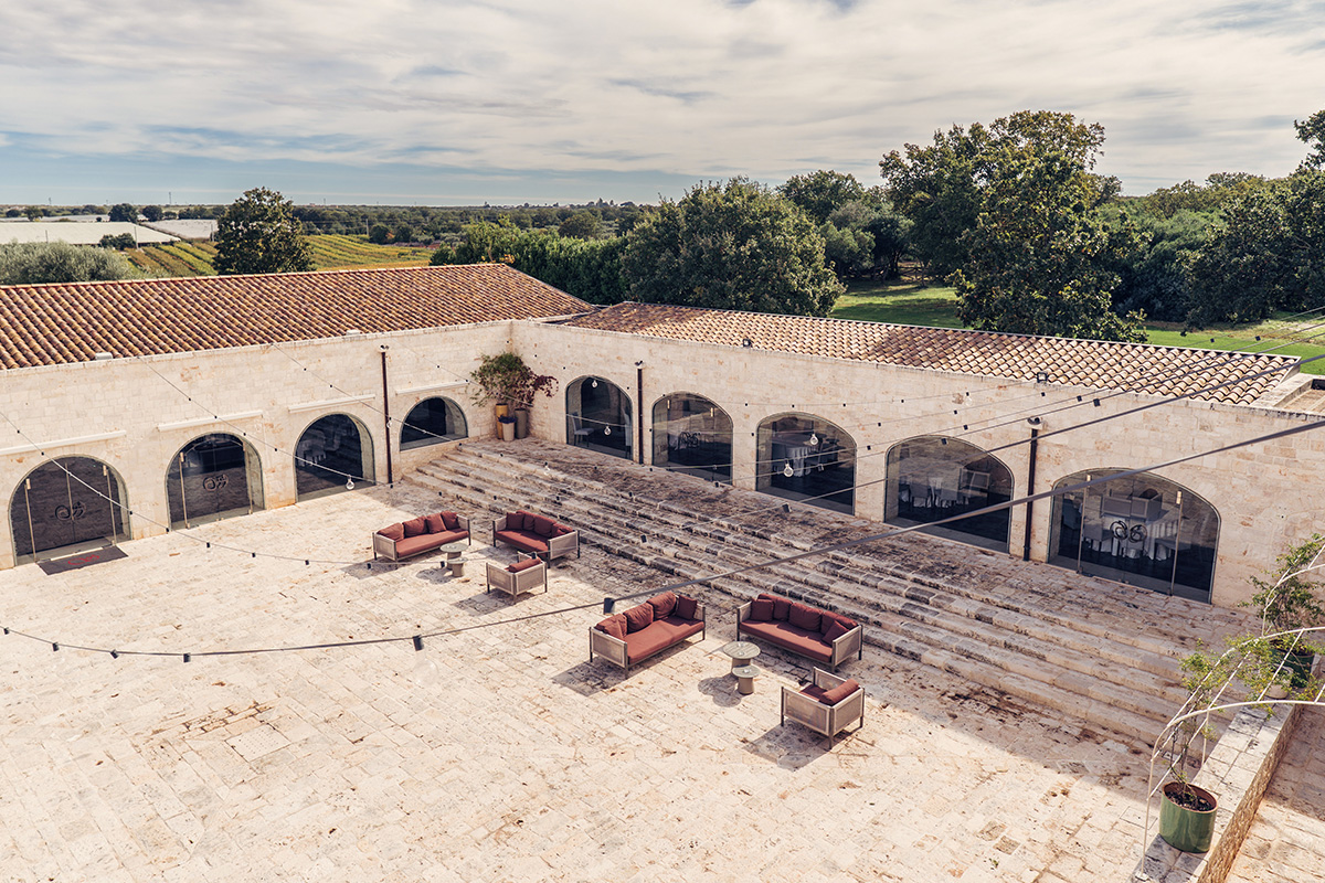 Aerial view of Il Santissimo Masseria courtyard with stone arches and outdoor lounge seating.