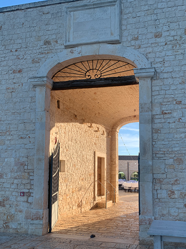 Stone doorway of Il Santissimo Masseria with sunlit courtyard beyond.
