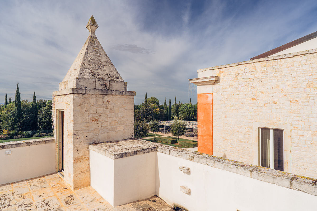 Rooftop terrace at Il Santissimo Masseria with stone walls and historic Puglian tower.