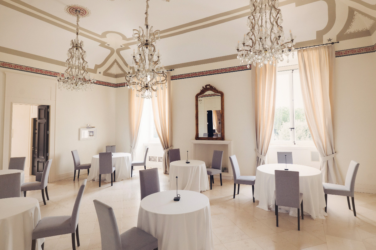 Elegant reception hall inside the historic Palazzo with chandeliers and round tables.