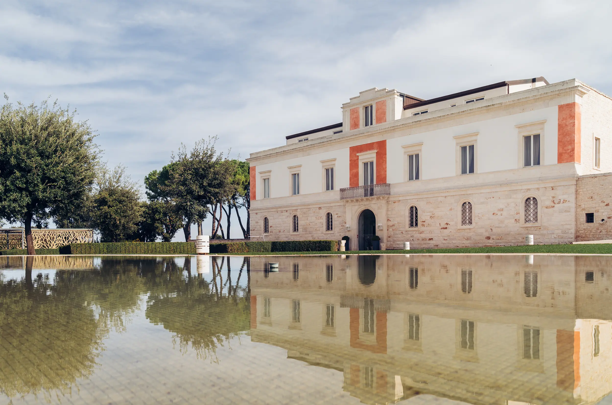 Facciata del palazzo storico de Il Santissimo a Turi, con riflesso sull’acqua.