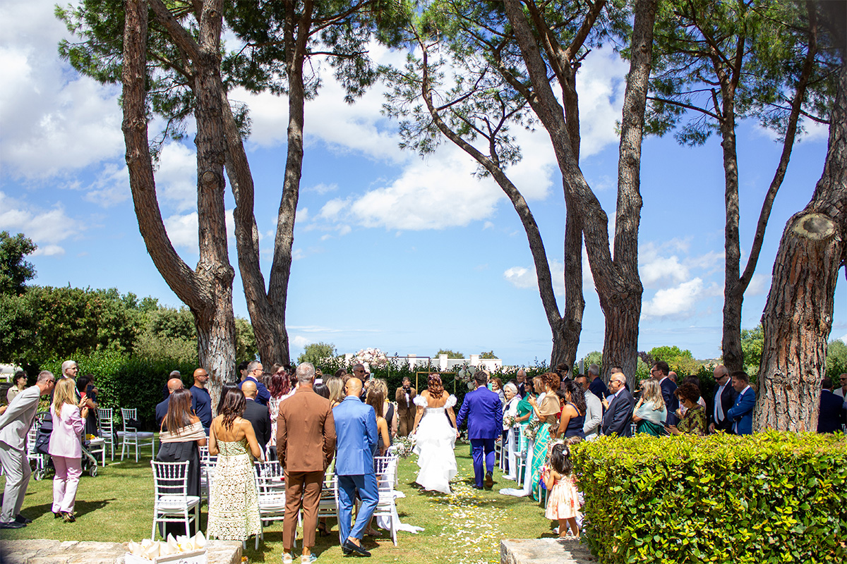 Outdoor wedding ceremony at the park of Il Santissimo with guests seated among trees and sea views.