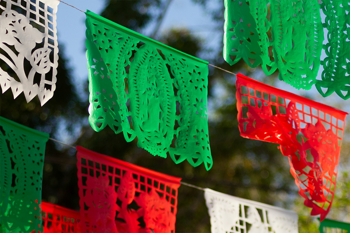Decorative green, white, and red flags hung in the park for a travel-themed wedding.