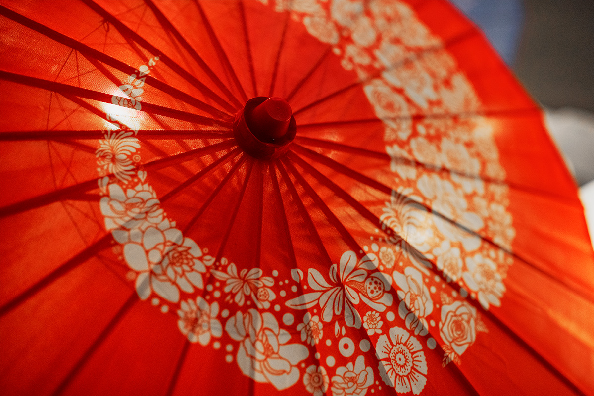 Red umbrella decorated for an oriental travel-themed wedding.