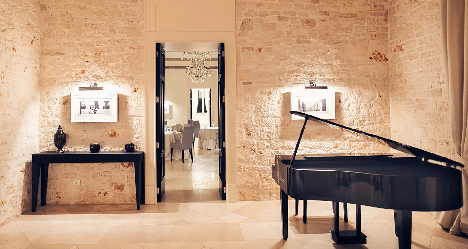 Sala in pietra con pianoforte a cosa e ingresso al ristorante.