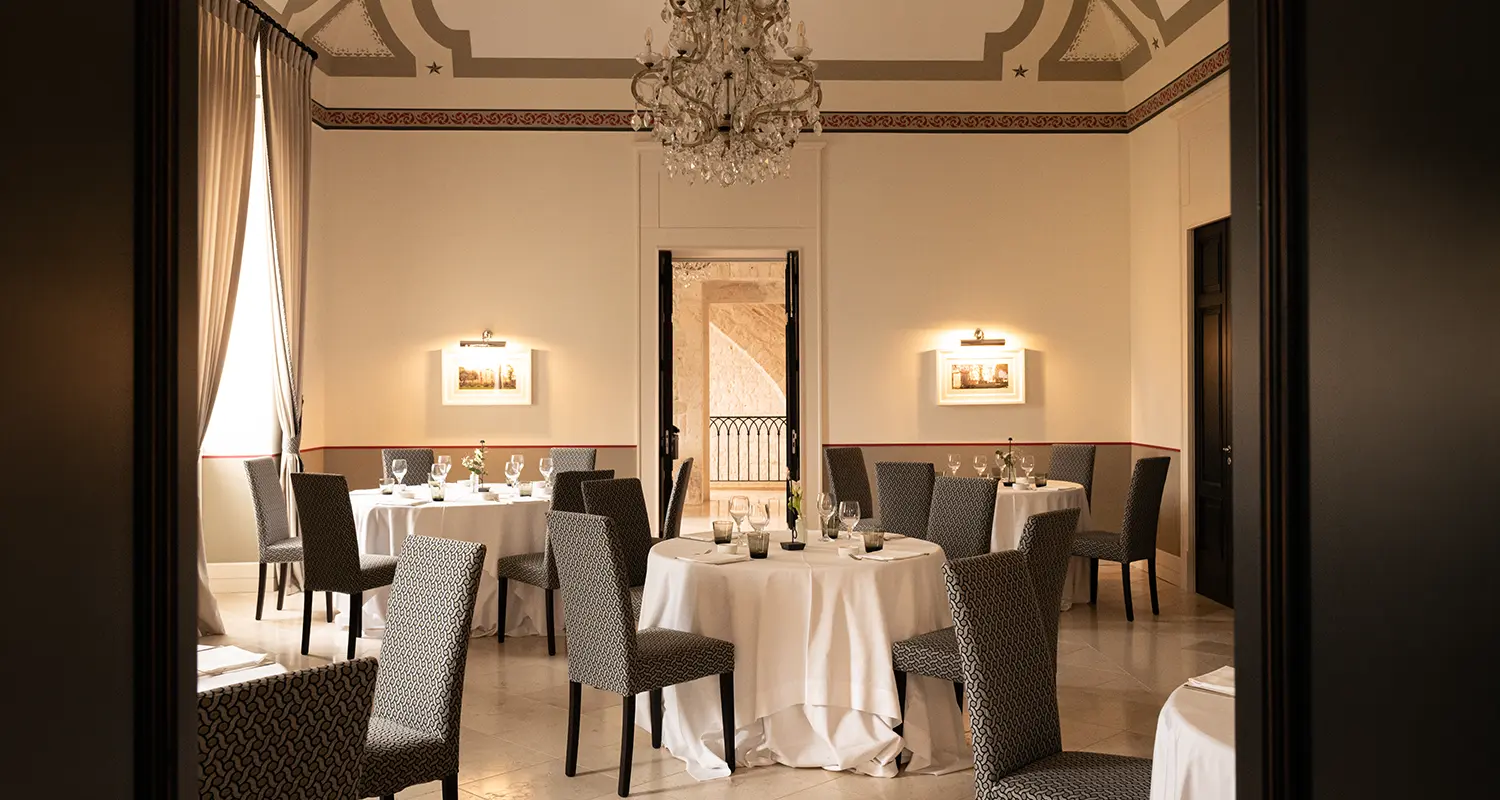 Sala del Ristorante Il Santissimo con tavoli apparecchiati, lampadario e arredi eleganti.